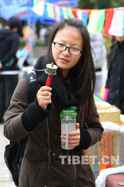 一名女生正在试着转转经筒。摄影：邓中华